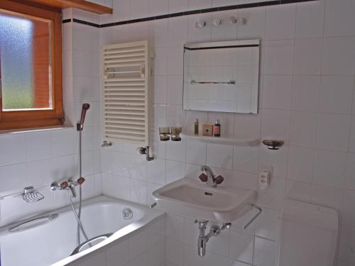 La salle de bains blanche est pourvue d'un lavabo et d'une baignoire. dans l'établissement Etoile du Sud 108, à Verbier