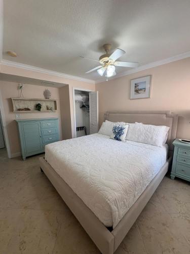 a bedroom with a bed with a ceiling fan and blue cabinets at Waves, Sun & Relaxation Retreat in Clearwater Beach