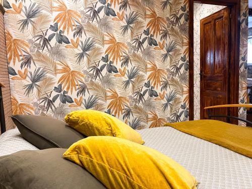 a bedroom with two beds with yellow pillows and a wallpaper at Alojamiento rural cerca de Bilbao in Basauri