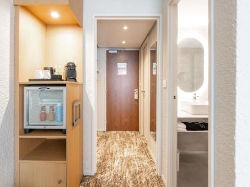 a hallway with a bathroom with a sink and a mirror at Novotel Grenoble Nord Voreppe in Voreppe