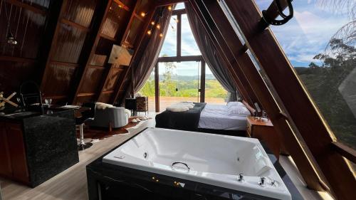 ein Badezimmer mit Badewanne und ein Bett in einem Zimmer in der Unterkunft Cabanas do vale in Itaquá