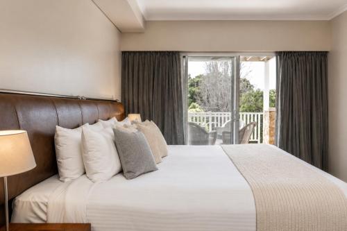 a bedroom with a large bed and a balcony at Caves House Apartments Yallingup in Yallingup