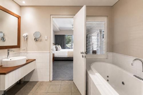 a bathroom with a tub and a sink and a bed at Caves House Apartments Yallingup in Yallingup