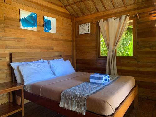 a bed in a log cabin with a window at Camp Olli Beach Villas in Dapa