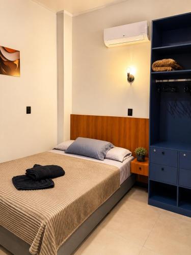 a bedroom with a bed and a blue cabinet at Studio Moderno e Novo - Cozinha Completa, Ar Condicionado e Wifi - Rápido Acesso ao Centro in Chapecó