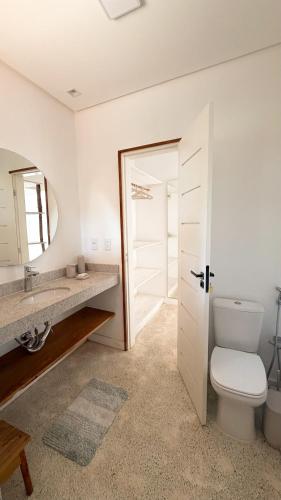 a bathroom with a toilet and a sink and a mirror at Vila Anambé in Uruçuca