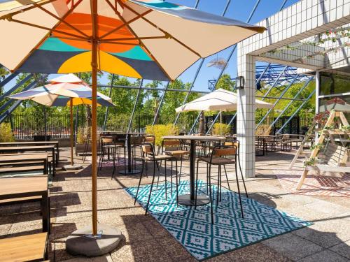 a patio with tables and chairs with umbrellas at ibis Styles Paris Bercy in Paris