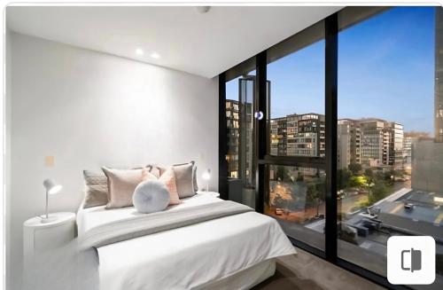 a bedroom with a white bed and a large window at City Vibe on Dorcas Southbank in Melbourne