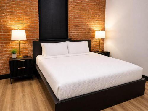 a bed in a room with two lamps and a brick wall at Brick & Bed Riverfront Lofts, T 303 in Saint Louis