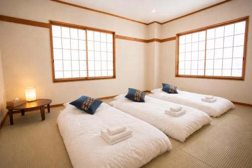three beds in a room with two windows at nozawasnow in Nozawa Onsen