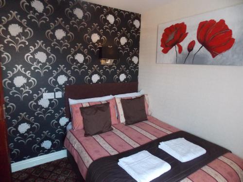 a bedroom with a bed with a red flower wallpaper at The Trafford Hotel in Blackpool
