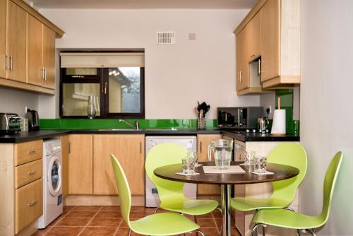 une cuisine avec des chaises vertes et une table dans l'établissement Cathedral View Apartments, à Longford