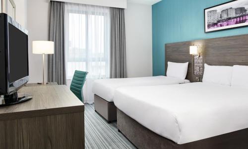 a hotel room with two beds and a television at Leonardo Hotel Cheltenham in Cheltenham