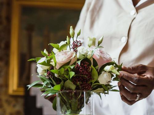 a man holding a vase with a bouquet of flowers at Papadopoli Hotel Venezia - MGallery Collection in Venice