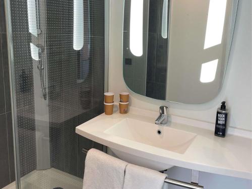 a bathroom with a sink and a shower with a mirror at ibis Colmar Centre in Colmar