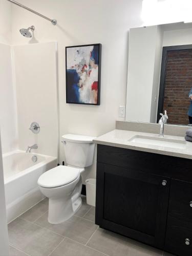 a white bathroom with a toilet and a sink at Brick & Bed Riverfront Lofts, T 308 in Saint Louis