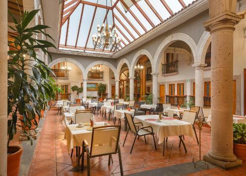 a restaurant with tables and chairs and a chandelier at Hotel Boutique Grand Mayes in Pátzcuaro
