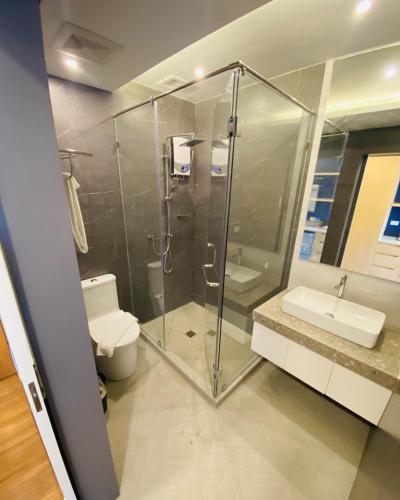 a bathroom with a shower and a toilet and a sink at Wyndale Hotel in Camalig