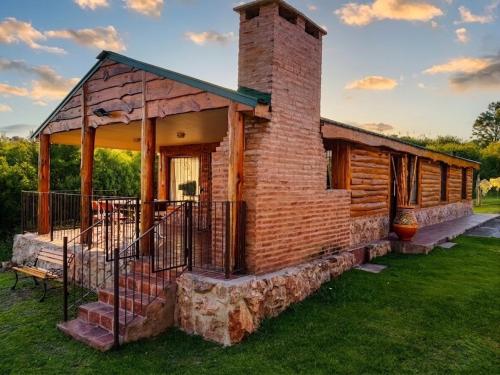 a log cabin with a brick chimney and a porch at Cabañas Lago Azul in Villa Santa Cruz del Lago