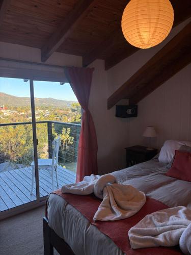 a bedroom with two beds and a balcony with a view at Altos del Pucara Piscina Climatizada vista a las sierras juegos Huerta Orgánica in Huerta Grande