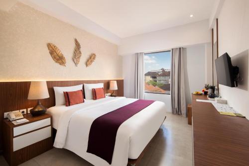 a hotel room with a large bed and a television at Nadi Hotel Legian in Legian