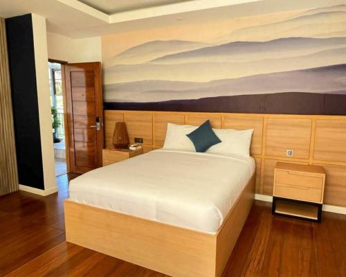 a bedroom with a bed with a painting on the wall at Wyndale Hotel in Camalig