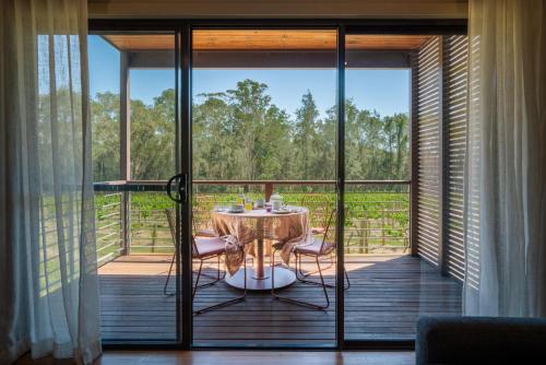 a room with a table and chairs on a balcony at Hermitage Lodge in Pokolbin
