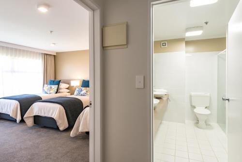 a hotel room with two beds and a toilet at Distinction Hamilton Hotel & Conference Centre in Hamilton