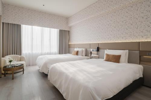 a hotel room with two beds and a table at T Hotel in Taichung