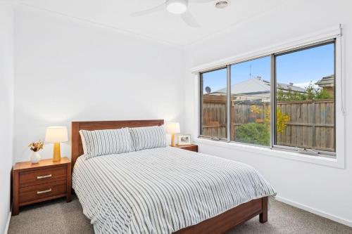 a white bedroom with a bed and a window at Point Retreat in Point Lonsdale
