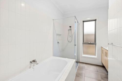 a white bathroom with a tub and a shower at Point Retreat in Point Lonsdale