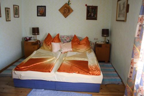 ein Schlafzimmer mit einem Bett mit orangefarbener Bettwäsche und Kissen in der Unterkunft Weinbau-Gästezimmer Martin und Eva Maria Jamek in Weissenkirchen in der Wachau