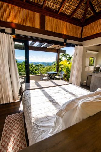 a bedroom with a large bed with a large window at Pousada Rosa Norte in Praia do Rosa