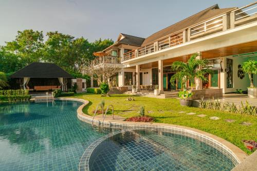 a house with a swimming pool in front of a house at Kiri Anda Villa Phuket in Rawai Beach
