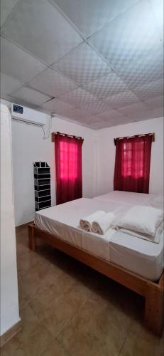 a bedroom with a large bed with red curtains at Casa de Nivia in Acequias Abajo