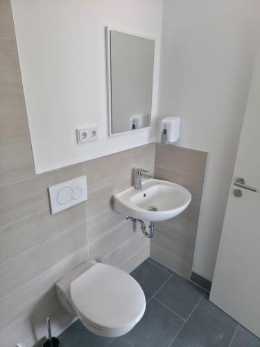 a bathroom with a white toilet and a sink at My Pension City Großaitingen - Augsburg in Großaitingen