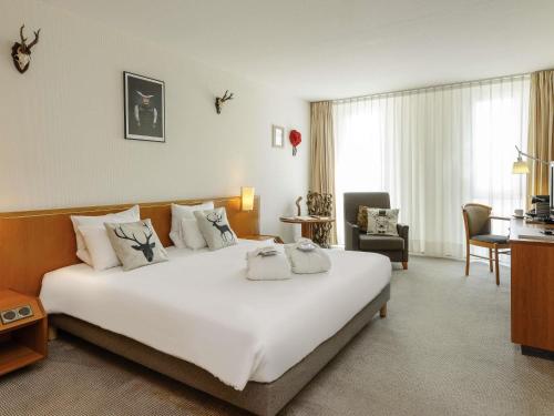 a hotel room with a large white bed and a desk at Novotel Freiburg am Konzerthaus in Freiburg im Breisgau