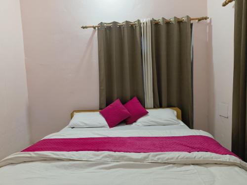 a bed with two pink pillows on top of it at Hotel Shubh Yatra in Nandaprayāg