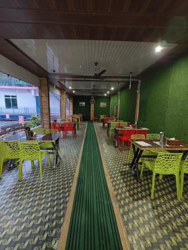 a restaurant with tables and chairs and green walls at Hotel Shubh Yatra in Nandaprayāg