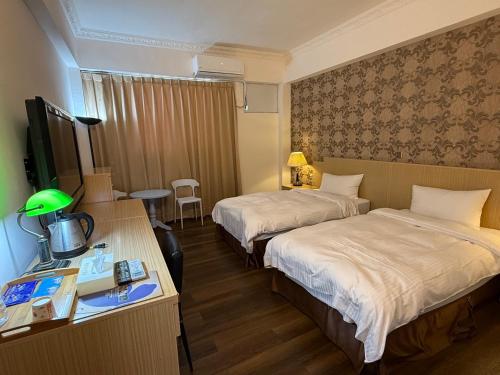 ein Hotelzimmer mit zwei Betten und einem Schreibtisch in der Unterkunft Dreamer Hotel in Budai