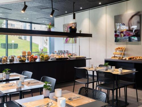 a restaurant with tables and chairs and a counter at Novotel Suites Genève Aéroport in Geneva