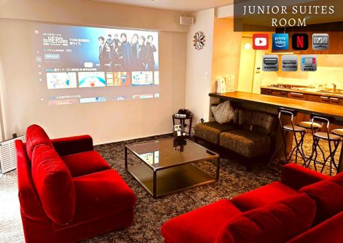 a living room with red couches and a large screen at Stay Hakata in Fukuoka