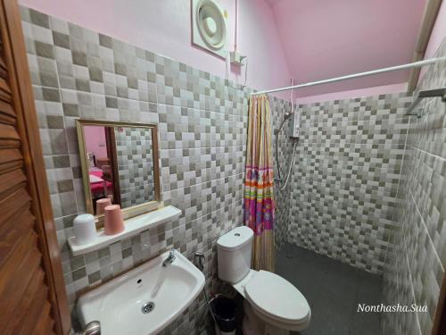 a bathroom with a sink and a toilet and a mirror at Bunrapee House in Nan
