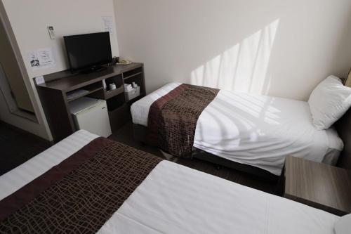 a hotel room with two beds and a television at Airport Plaza Hotel in Tomisato