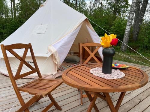 a table and chairs on a deck with a tent at Ilmjärve Glamping Otepää in Ilmjärve