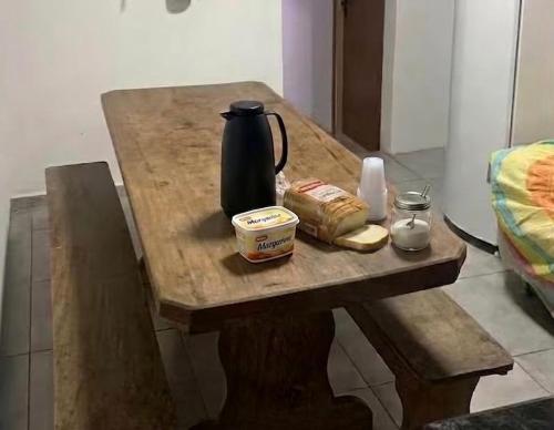 a wooden table with a tea kettle and bread on it at Hotel Airton in Ivaiporã