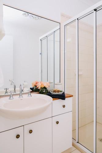 a white bathroom with a sink and a shower at Suma Park Estate in Point Lonsdale