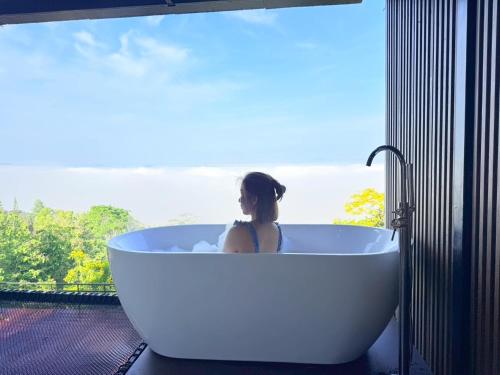a woman sitting in a bath tub in front of a window at Heaven Khaokho2 in Khao Kho