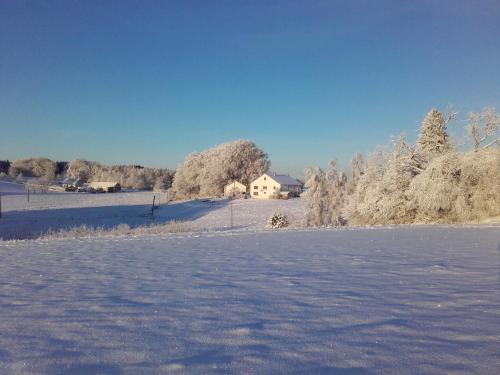 a snow covered field with a house in the background at Gîte Les Hirondelles in Plombières-les-Bains