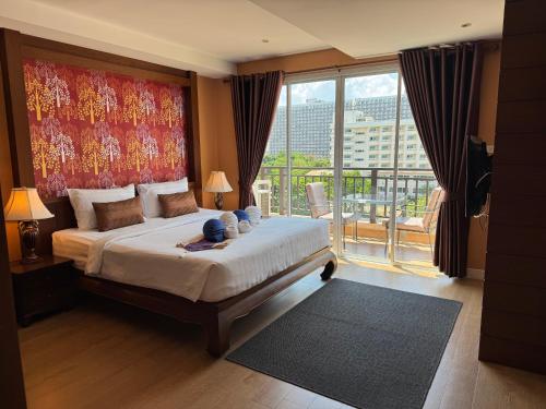 a bedroom with a large bed and a balcony at Jomtien Beach Penthouses in Jomtien Beach